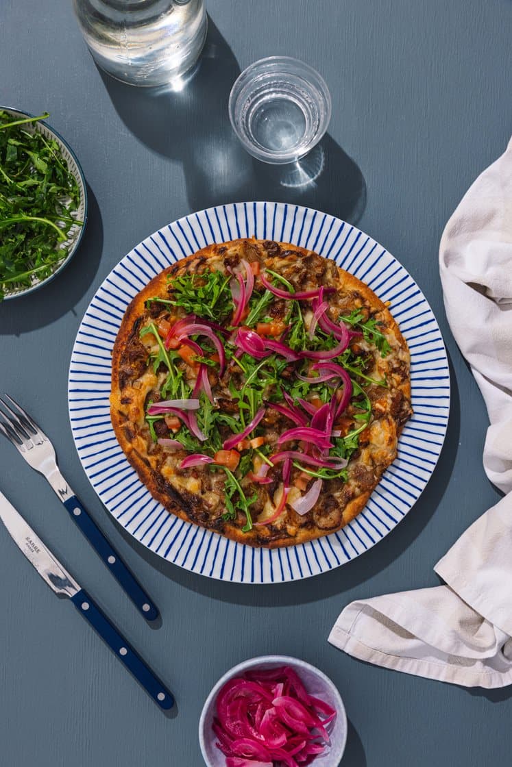 Steinovnsbakt hvit pizza med gyroskjøtt, syltet rødløk og ruccola