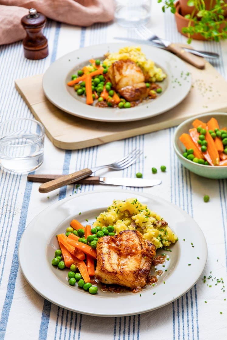 Stekt torskefilet og grovknuste poteter med gressløk, gulrøtter, erter og brunet løksmør