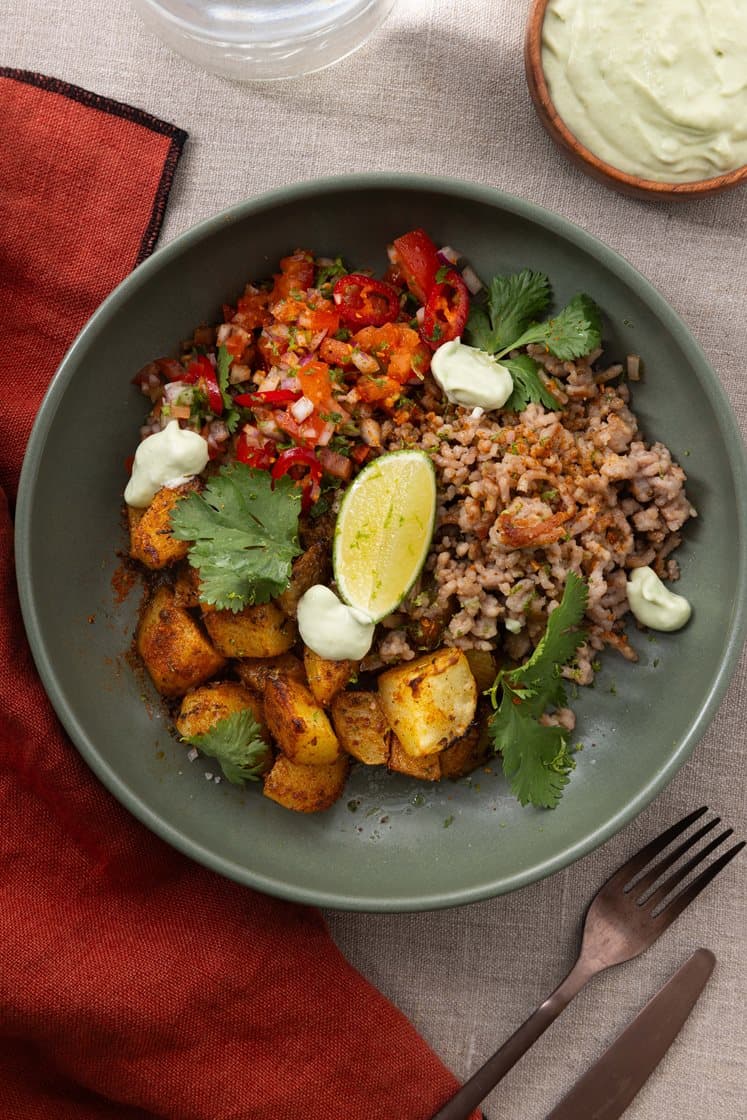 Bowl med tacokrydrede poteter og svinekjøttdeig, servert med avokadokrem og frisk tomatsalsa 