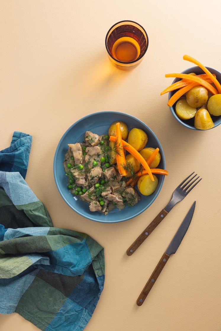 Dillkjøtt av mørkokt svinebog servert med grønne erter, kokte gulrøtter og poteter